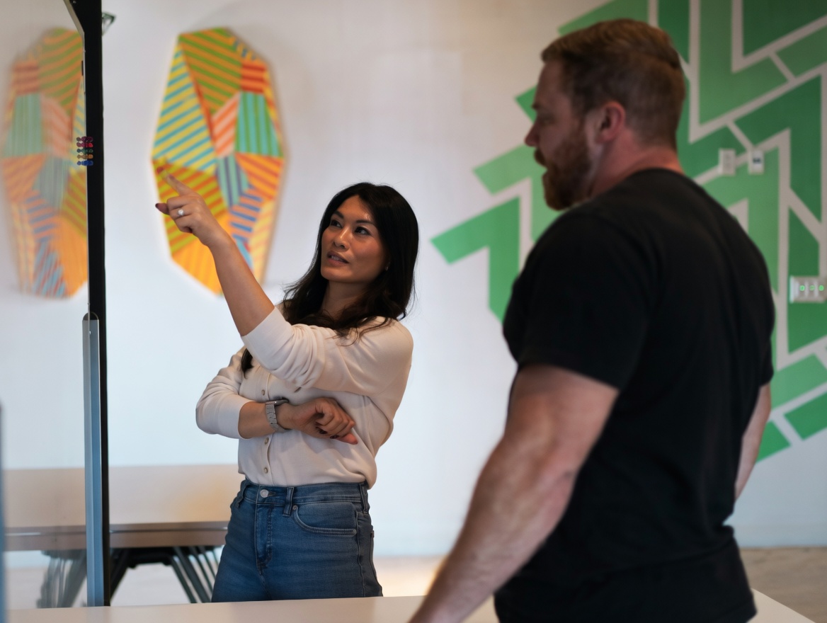 Two business analysts working out project details on a whiteboard