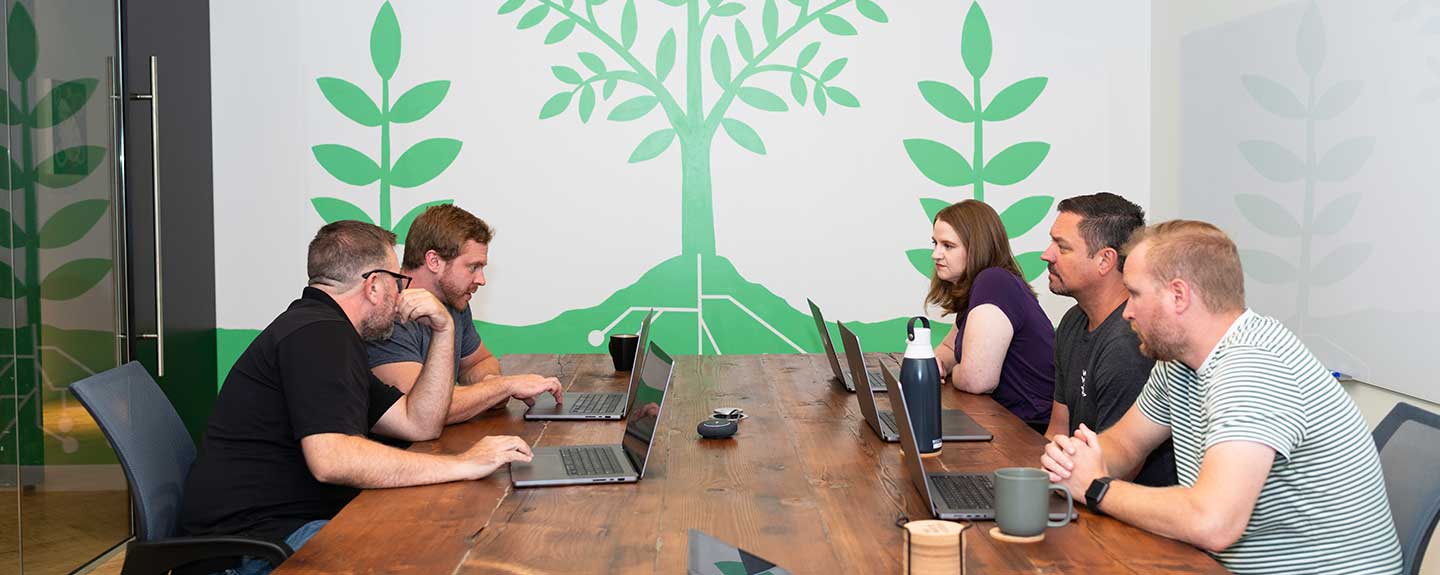 People sitting at a table with laptops, brainstorming.