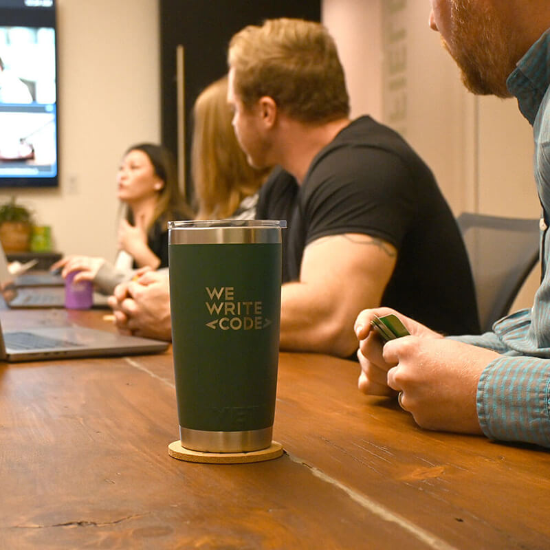 Close up of a We Write Code Yeti mug during a meeting