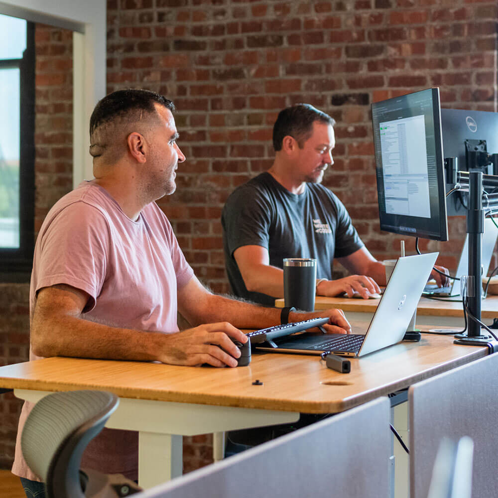 two developers collaborating at their standing desks