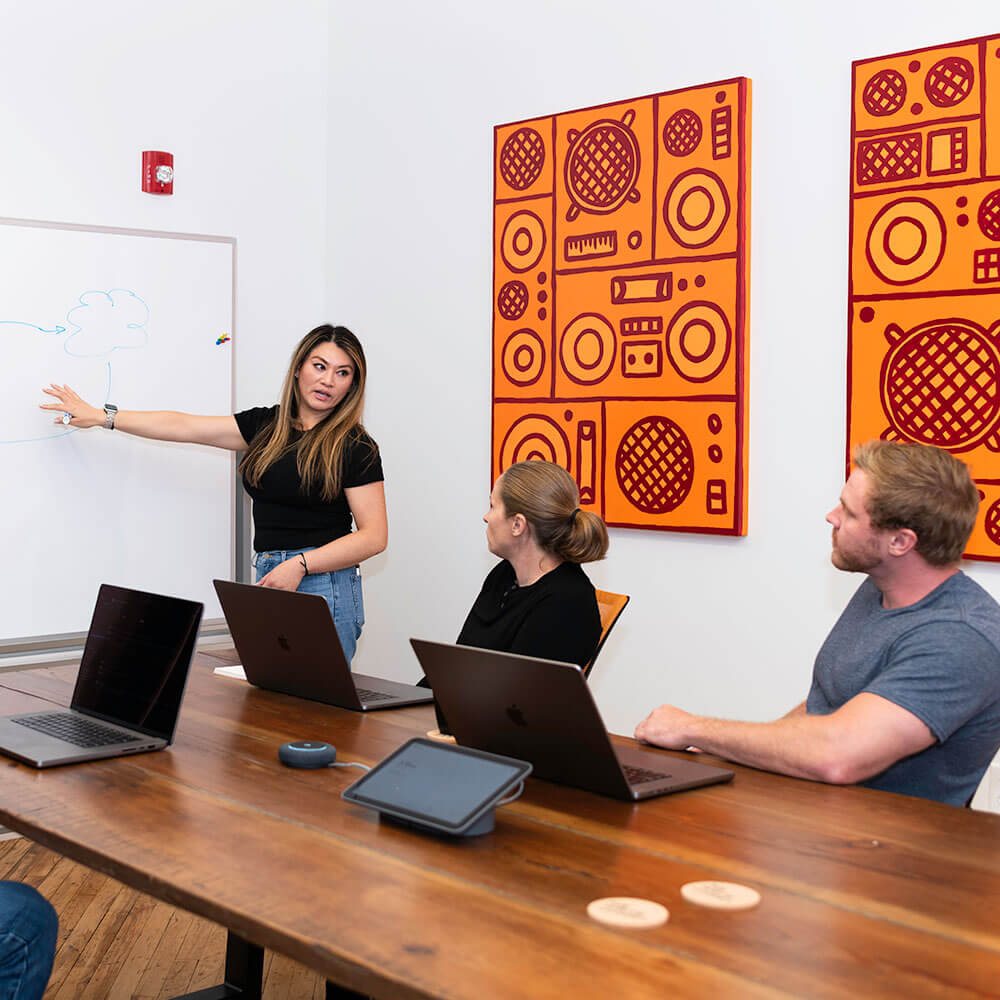 woman presenting a whiteboard diagram to her team